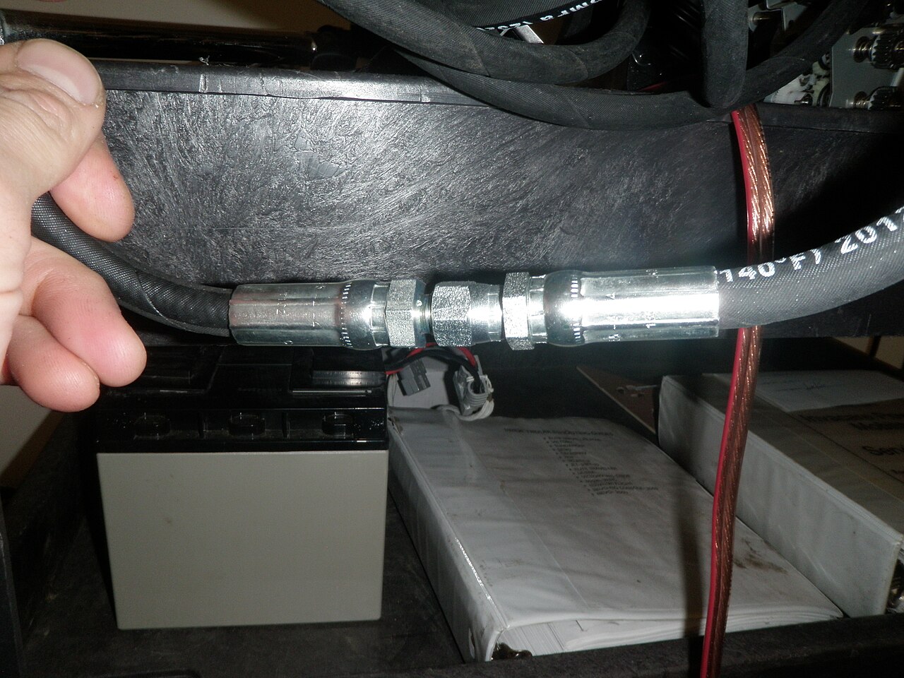 Crimped metal hydraulic hose fittings joining black pressure hose