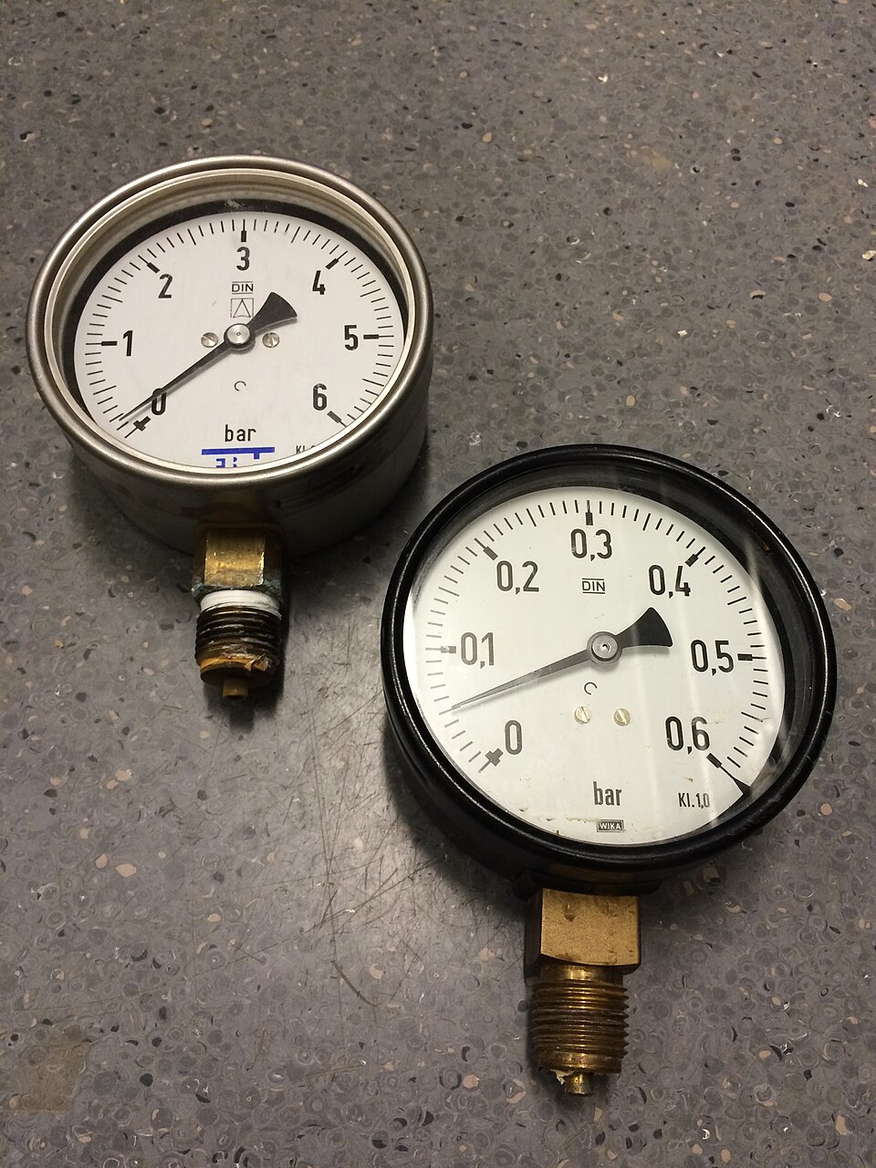 Two round industrial pressure gauges with metal fittings
