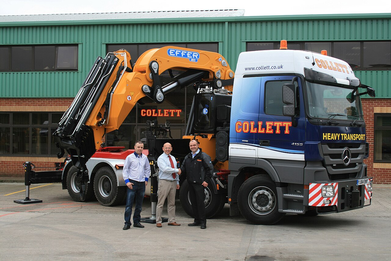 Orange articulated truck-mounted crane on a heavy transport vehicle