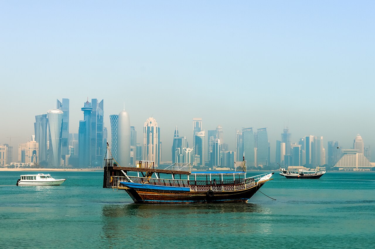 Traditional wooden dhow on Doha Bay with a distant city skyline