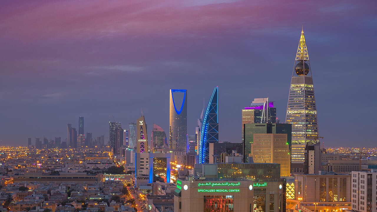 Riyadh skyline at dusk with illuminated towers under a purple sky
